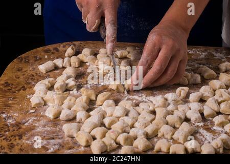two hands cutting a dough for making gnocchi. traditional italian dish Stock Photo