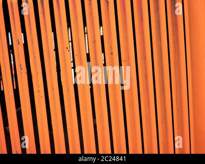 Rust speckled dark orange painted vertical metal slats Stock Photo