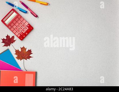 Stationery accessories: writing books, pens, and  calculator on grey background. Top view with copy space.  Various school accessories for children's Stock Photo