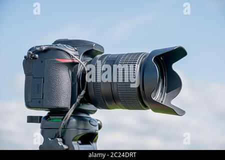 Camera with lens attached mounted on the top of a tripod Stock Photo