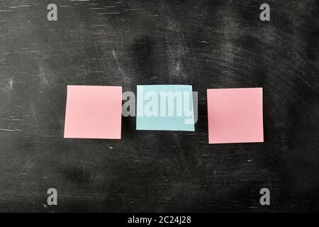 three blank paper stickers are stuck to a black wooden board,  copy space Stock Photo