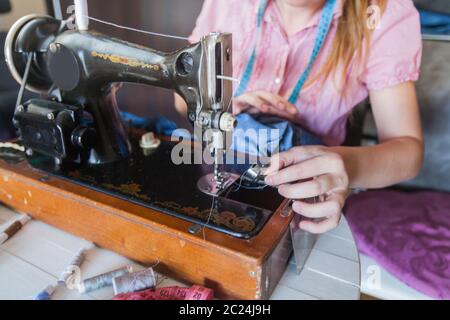 Closeup of female tailor hands changing thread on old sewing machine at home Stock Photo