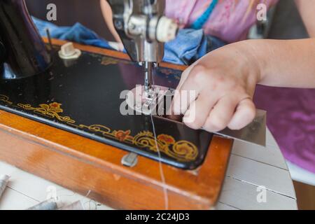 Closeup of female tailor hands changing thread on old sewing machine at home Stock Photo