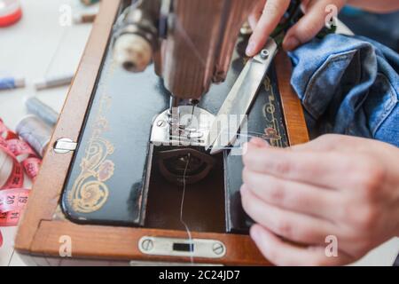 Closeup of female tailor hands changing thread on old sewing machine at home Stock Photo