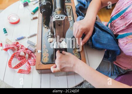 Closeup of female tailor hands changing thread on old sewing machine at home Stock Photo