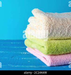 stack of multi-colored new terry bath towels on a blue wooden background , copy space Stock Photo