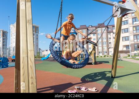 Two girls swinging strongly on a big round swing Stock Photo