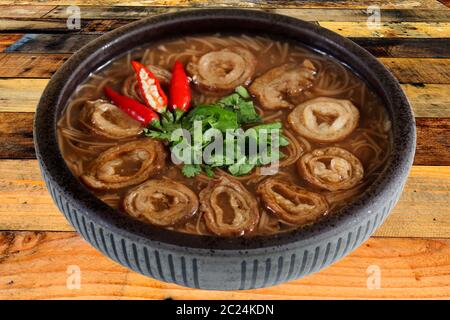 The brown color vermicelli with pork intestine on black bowl isolated on white background. Traditional Taiwan food Stock Photo