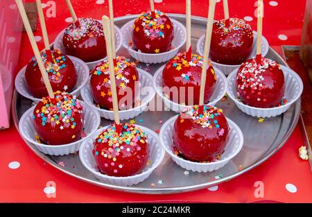 Sweet glazed red toffee candy apples on sticks for sale on farmer market or country fair. Thanksgiving and Halloween homemade red caramel glazed Stock Photo