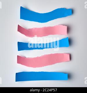 pink and blue torn strips of paper on a white background, flat lay Stock Photo