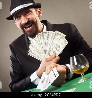 The happy gambler is lucky in poker card and winning cash prize in casino. Stock Photo