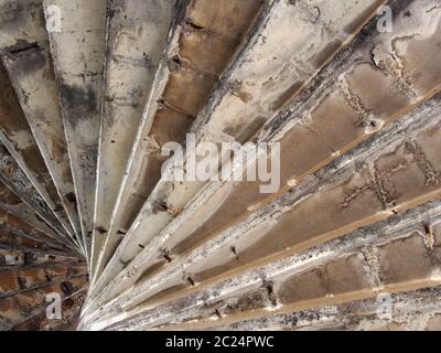 a view underneath old eroded brown worn concrete spiral stairs forming a geometric abstract Stock Photo