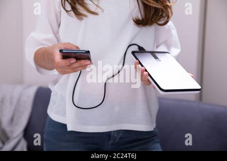 Mid-section Of Woman Using External Hard Disk For Data Transfer Stock Photo