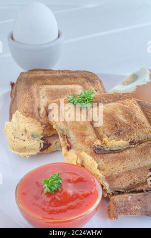 Toasts and egg with souce on white plate and wood Stock Photo