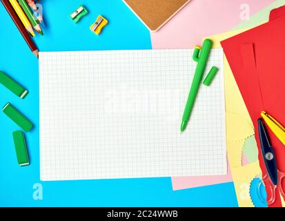white squared paper from notebooks, wooden colored pencils on a blue background, back to school Stock Photo