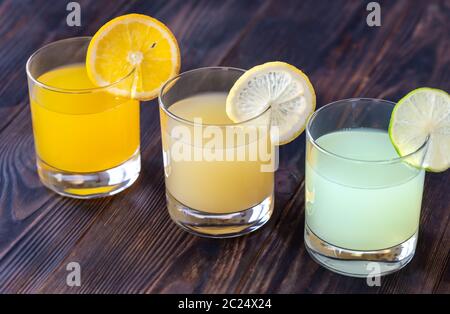 Assortment of citrus juices on the wooden background Stock Photo