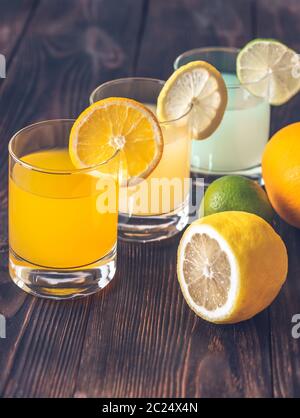 Assortment of citrus juices on the wooden background Stock Photo