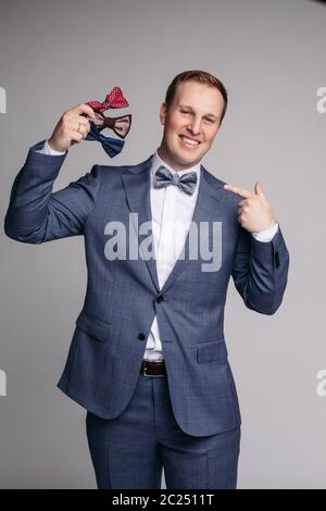 Smiling man insmart suit keeping bow ties in hand Stock Photo