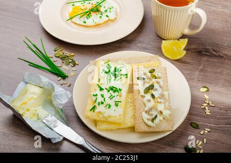 Crisp Crispbread with curd cheese spread with chives and seeds, fried egg and morning tea Stock Photo