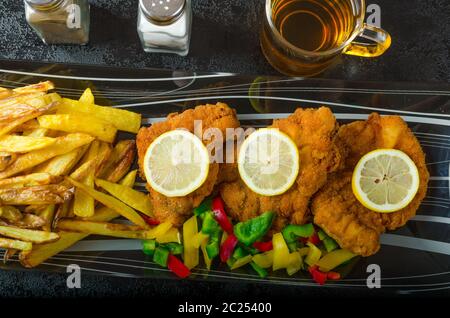 Schnitzel with french fries, homemade, platter, czech beer, vegetable, lemons Stock Photo