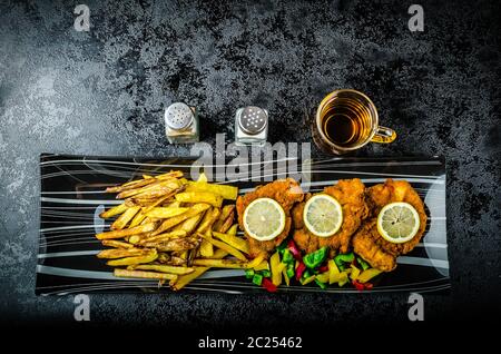 Schnitzel with french fries, homemade, platter, czech beer, vegetable, lemons Stock Photo