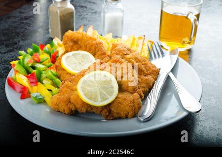 Schnitzel with french fries, homemade, platter, czech beer, vegetable, lemons Stock Photo