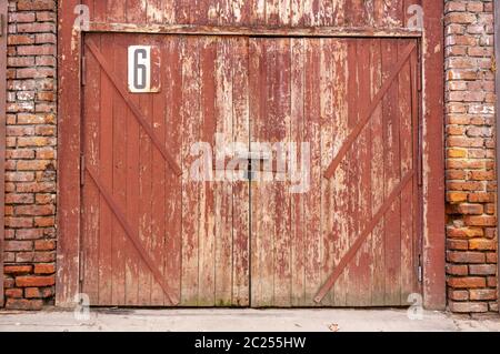 Old garage door in a white concrete wall. Gates made of wood painted with cracked green paint Stock Photo