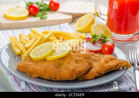 Schnitzel with french fries and a spicy dip, fresh from red orange Stock Photo