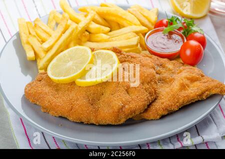 Schnitzel with french fries and a spicy dip, fresh from red orange Stock Photo