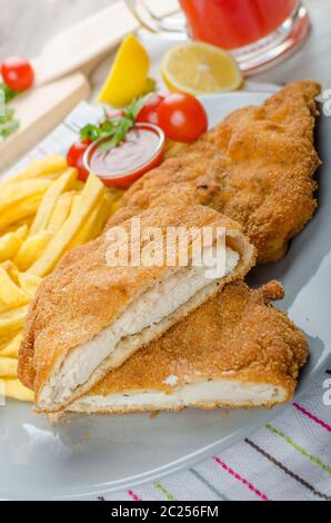 Schnitzel with french fries and a spicy dip, fresh from red orange Stock Photo