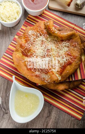 Traditional carnival fast food specialty, fried yeast dough with cheese, ketchup and garlic Stock Photo