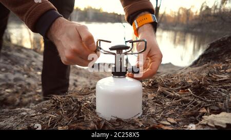 Hands caucasian male traveler, tourist sits in the forest near the lake camping. Uses inventory for cooking. A hand lighter set Stock Photo