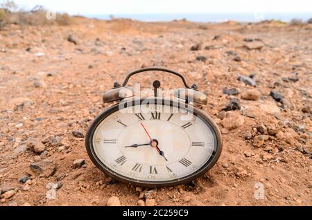 Classic Analog Clock In The Sand On The Rock Desert Stock Photo