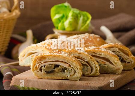 Roll out puff pastry stuffed with mushrooms, cheese and ham Stock Photo