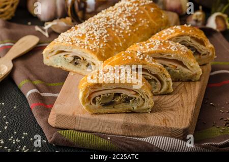 Roll out puff pastry stuffed with mushrooms, cheese and ham Stock Photo