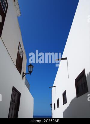 street of traditional white houses in perspective view looking upwards with bright blue summer sky Stock Photo