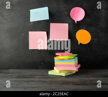 stack of multi-colored sticky stickers on a black wooden background, concept back to school Stock Photo