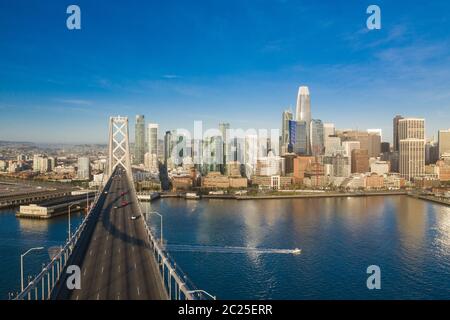 Aerial view of the San Francisco, California, skyline at sunrise. Ample copy space in blue sky. Bay bridge in foreground on the left side of the frame.