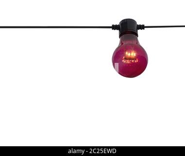 An outdoor string light with white bulb hanging above green foliage and ...