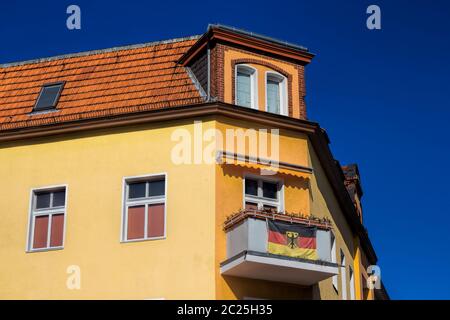 Renovated old building with German flag on the balcony in Berlin, Germany Stock Photo