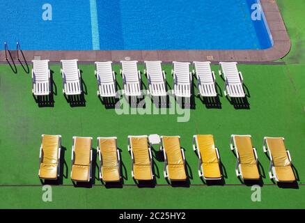 view of an outdoor swimming pool from above with sun loungers an sunlit ripples on the water Stock Photo