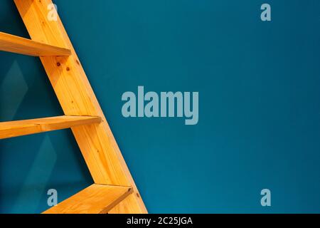 wooden yellow ladder on blue wall background. colorfull interior abstract space for text Stock Photo