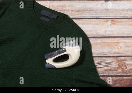 wool sweater with electric lint remover on wooden background Stock Photo