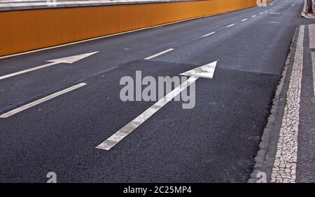 large white arrows painted on a black two lane road with stripes along the curb Stock Photo