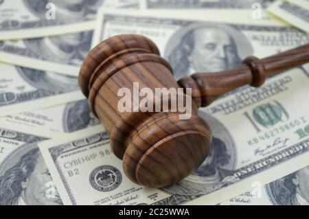 An image focused on the legal side of monetary gains using a gavel and an abundance of American cash as a background. Stock Photo