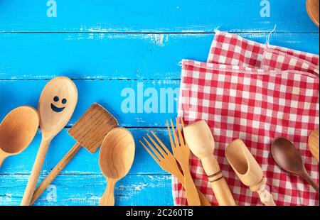 many different wooden spoons, forks  on a blue background, copy space, kitchen backdrop Stock Photo