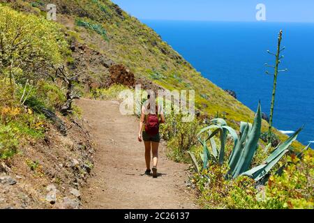 Young hiker woman walking on a trail overlooking the sea in Tenerife Stock Photo