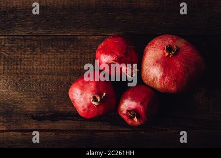 Four ripe pomegranate on rustic wooden table Stock Photo