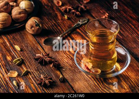 Spiced tea with star anise, cardamom and dried lime in armudu glass over wooden surface Stock Photo