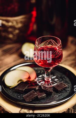 Homemade red currant nalivka and chocolate with sliced apple on metal tray Stock Photo